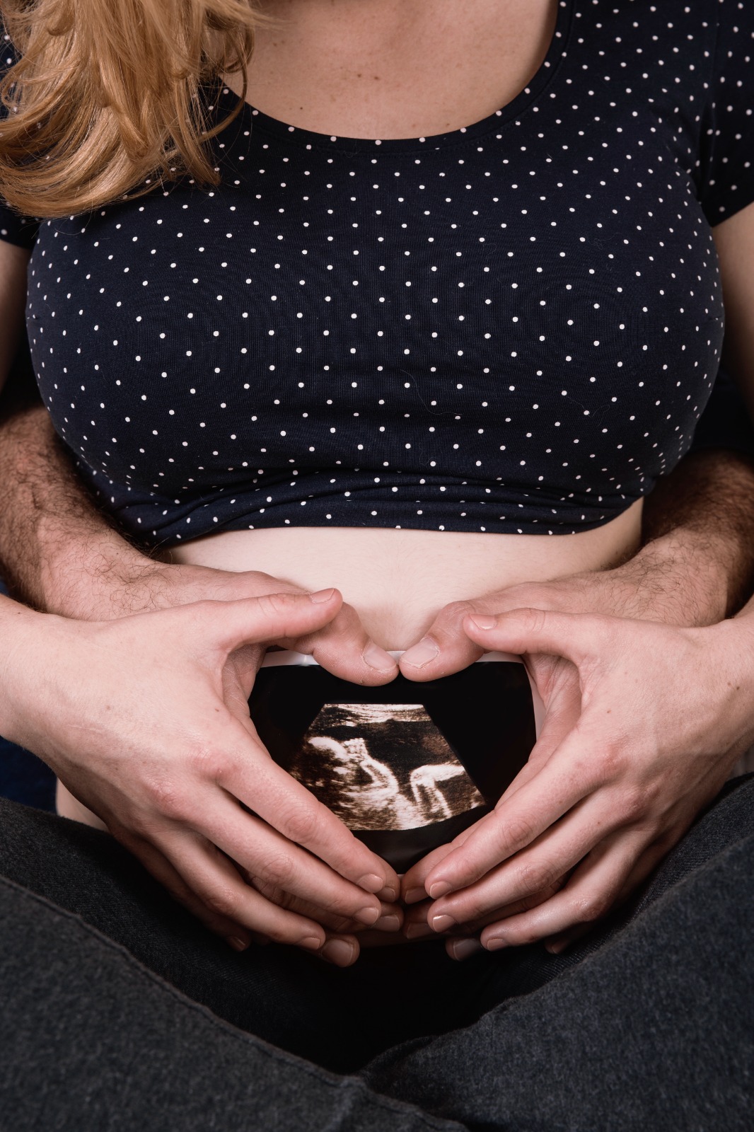 Aanstaande ouders met de handen in een hartvorm op een beschilderde zwangere buik